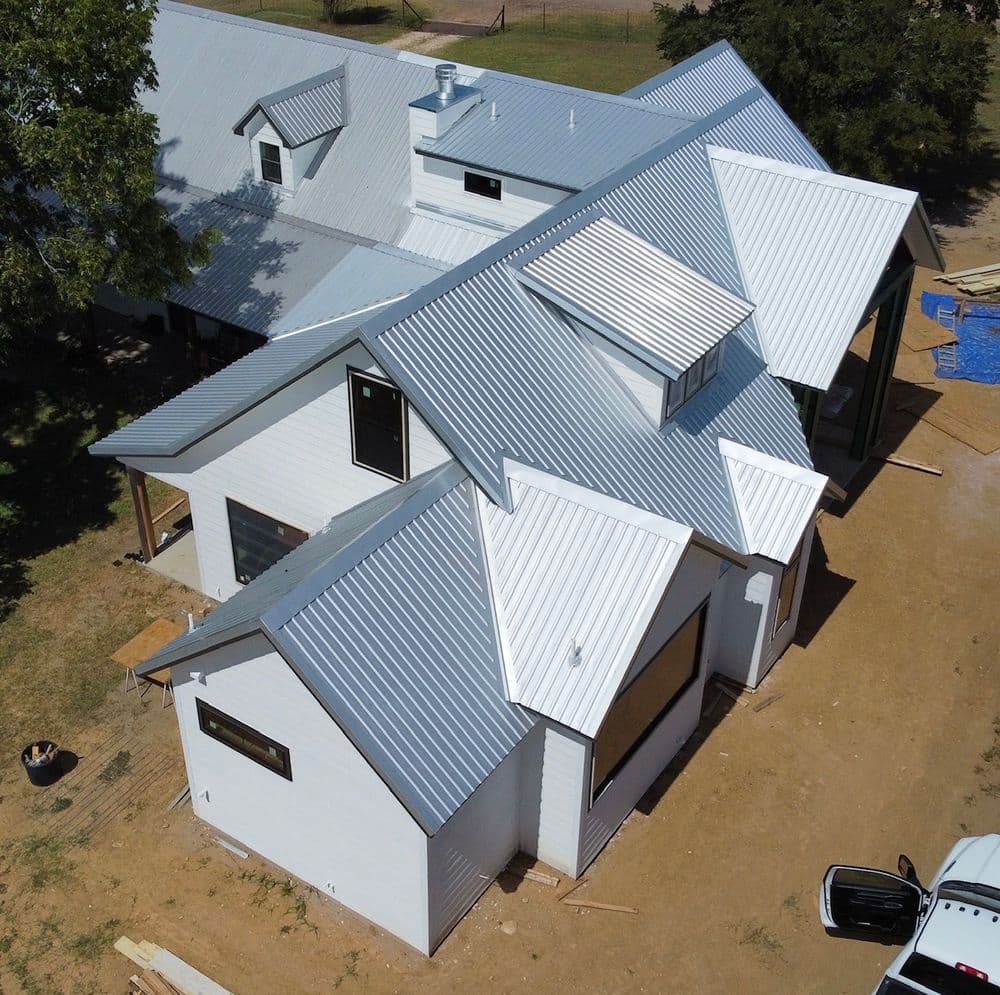 Aerial view of a modern home with metal roofing and a spacious layout under construction.