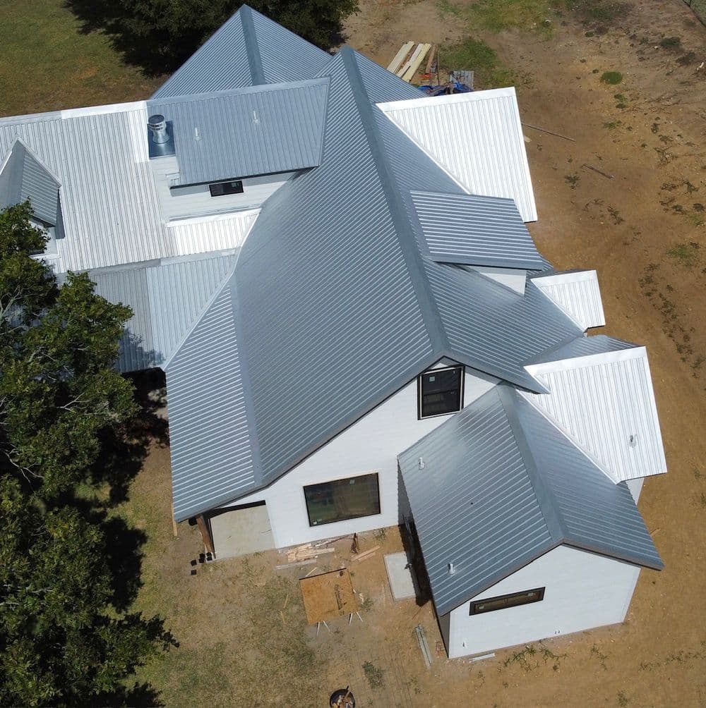 Aerial view of a modern home with multiple gabled roofs and metal roofing.