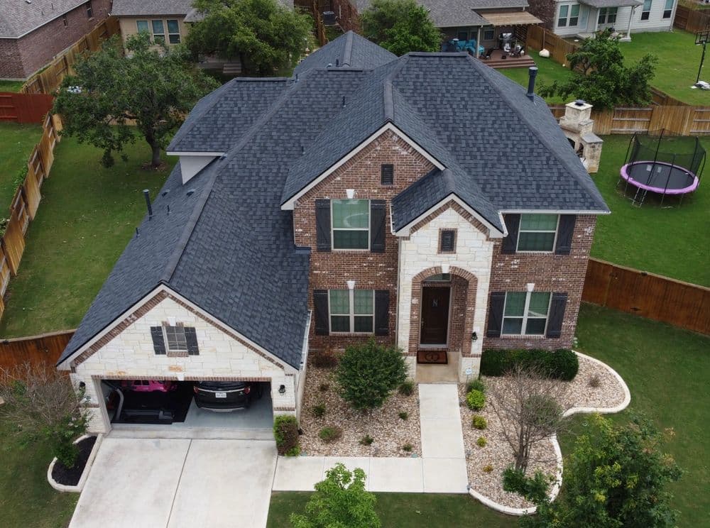 Aerial view of a modern two-story brick home with landscaped yard and driveway.