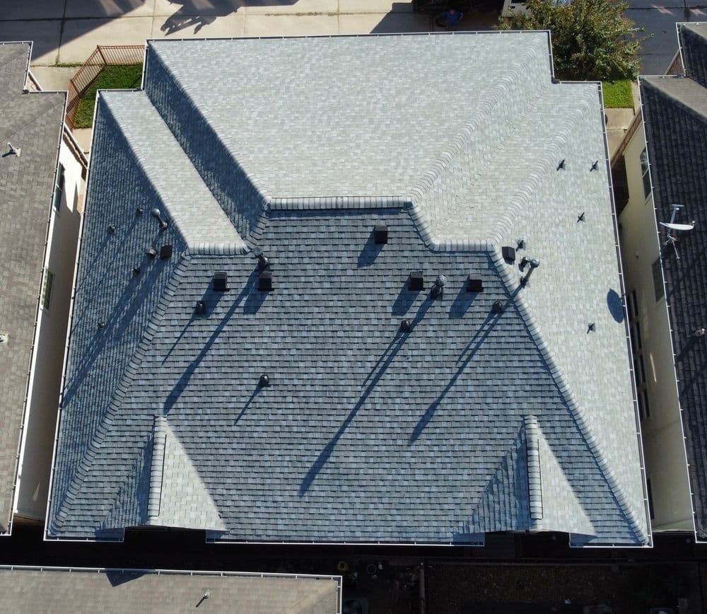 Aerial view of a multi-pitched shingle roof showcasing its intricate design and shadows.