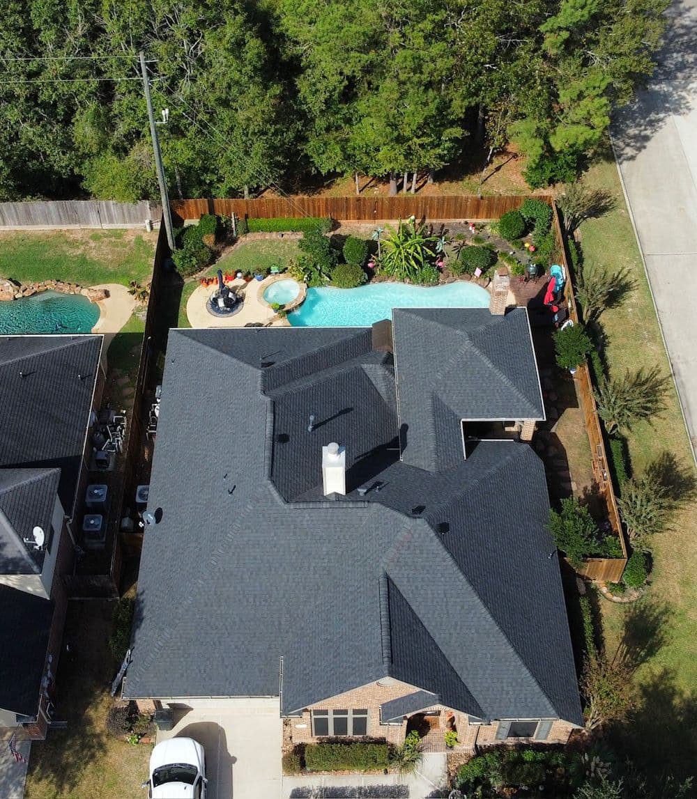 Aerial view of a modern home with pools and landscaped backyard in a sunny neighborhood.