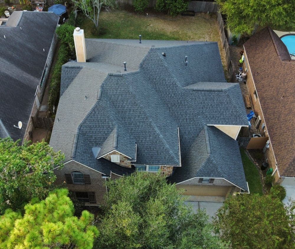 Aerial view of a modern home with multiple roof angles and surrounding greenery.