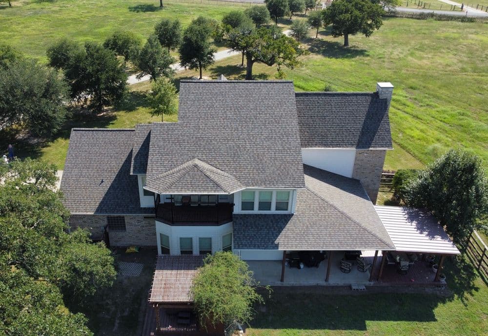Aerial view of a modern two-story house with a manicured lawn and surrounding trees.